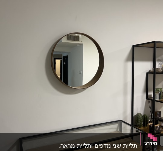 מראה עגולה תלויה על קיר לבן